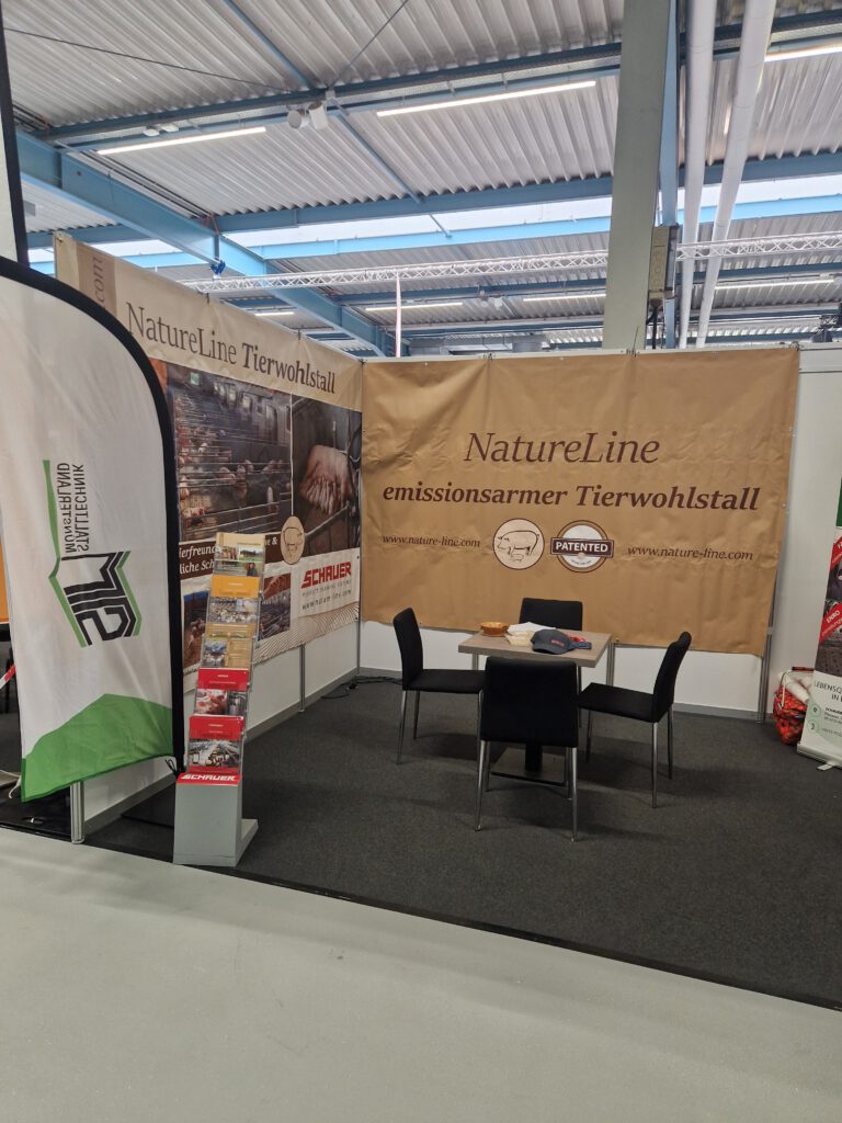 Zu sehen ist ein Messestand mit einer Beachflag "Stalltechnik Münsterland" im Vordergrund